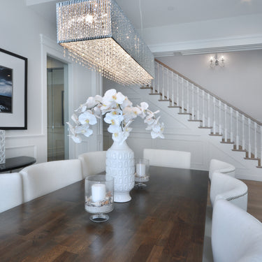 ET2 Spiral rectangular crystal bead pendant over a dark wood table with a vase of white flowers and a staircase behind