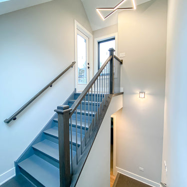 ET2 Stealth black angular channel pendant hanging above a stairwell with dark wood railing