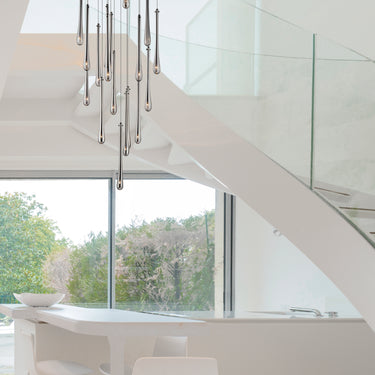 ET2 Stillo glass teardrop pendants hanging in a cluster beside a white curved stair and glass railing