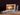 Conmoto Teras Fireplace Tools with Stand, beside a modern fireplace with a log holder
