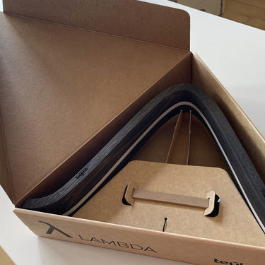 Lambda lamp by Teukho in Black resting in its open shipping box