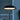 Lit disc shade of the black Tepa Short Accent table lamp at dusk against a blue window