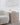 Caspe Alabaster 7 lamp lit on a side table next to a curved armchair