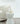 Caspe 8 lamp with the tapered crystal narrow end down, lit on a white side table