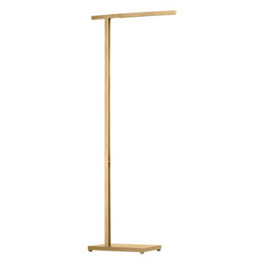 Stagger 46-inch floor lamp in natural brass, creating a soft, warm glow in a minimalist bedroom.