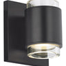 Voto modern round LED wall light in black finish, illuminated with warm 3000K light, mounted vertically on a hallway wall.