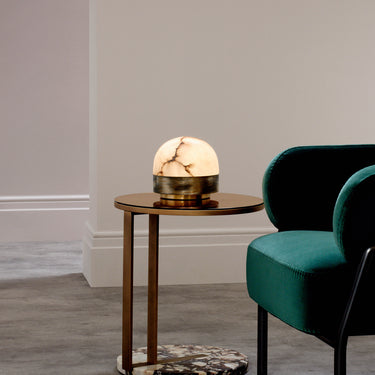 Lucid table lamp with a honed alabaster dome on a brass base, in a room setting