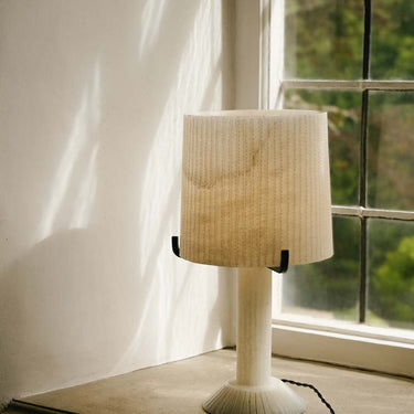 Acropolis table lamp on a sunlit window ledge beside a leaded window
