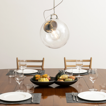 Artemide Miconos Gold pendant light with clear glass globe installed on top of a dining table