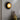 Carapace wall light glowing on a gray wall above a console with a gold vase
