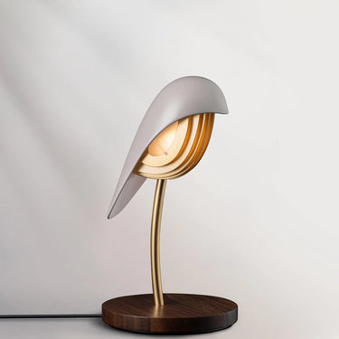 Daqiconcept Bird LED Dimmable Desk Lamp - Almond Beige illuminating a book on a bedside table