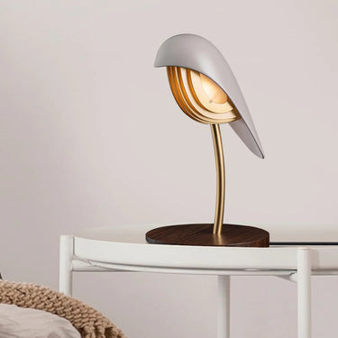 Warm, inviting light from Daqiconcept Bird LED Dimmable Desk Lamp - Almond Beige in a cozy reading nook