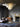 Nimbus chandelier hanging in a dark living room with a fireplace and a leather chair