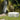 White Arc curved bench on a lawn in front of a rock wall and waterfall