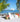White Puck round ottoman beside a Check chair with a colorful throw on a beach with sailboats
