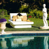White Crib queen daybed with Lean wedge headboards and tan pillows on a lawn beside a pool with a classical statue