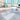 White Dash benches and Dot 2 cubes on a plaza beside a circular lounge and high-rise towers