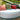 White Roll bolster along the back of a Moon Pad daybed with coral and green pillows beside a reflecting pond