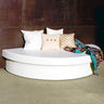 White semi-circle Moon Pad daybed against a dark wall with white and striped pillows and a patterned throw