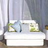 Spa Club Now cabana set with a white queen resort bed, patterned pillows and two cylinder ottoman side tables under sheer curtains