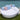 White Sun Pad round daybed by a pool with blue and white striped pillows