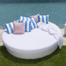 White Sun Pad round daybed by a pool with blue and white striped pillows