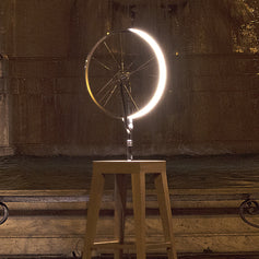 Marcel by Cyclampa glowing at night, a ring of light on an oak stool