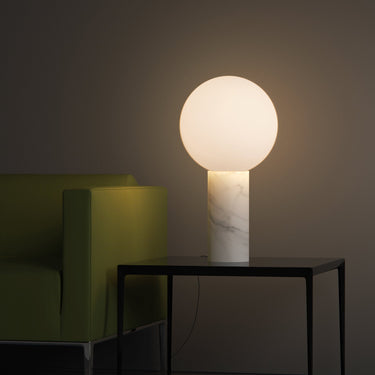 Pilar table lamp by Pablo beside a green sofa