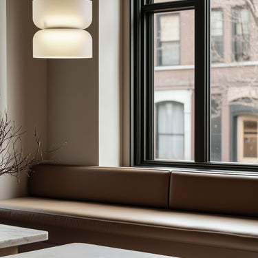 Totem Mini up/down pendant by Pablo over a marble table by a window bench
