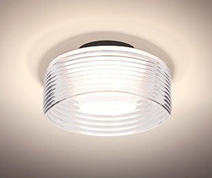 Belu Clear drum glowing on the ceiling, ribs catching the light | Besa Lighting