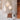 Three white Hive and Nest cardboard pendants at different heights beside a sofa and a wooden shelf