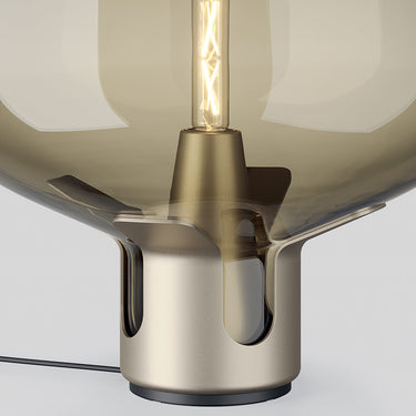 Close-up of the Flar table lamp's honey-colored glass shade and elegant terra finish steel base.
