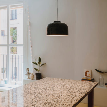 Black ceramic pendant lamp hanging above modern dining table with black canopy