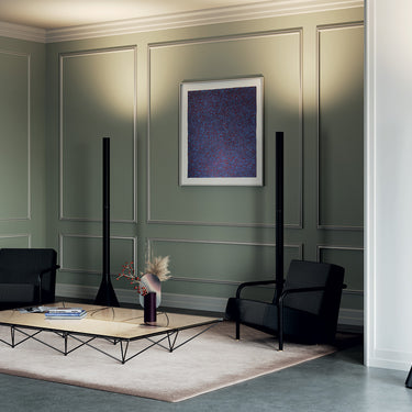 Designer floor lamp, Croma by Luca Nichetto, casting an inviting warm glow against a wall.