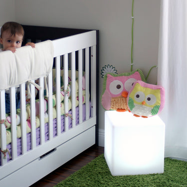 White Cube lamp (14 in) beside a white crib with flowers on top of the cube